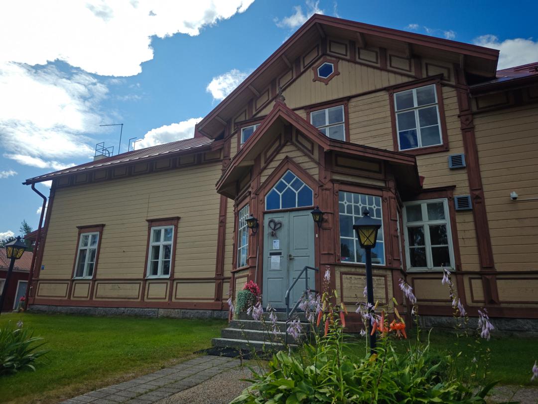 Pappila, jonka edessä kukkia ja taustalla sininen taivas